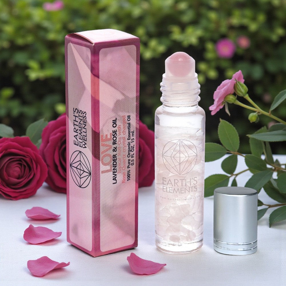 Earth's Elements Lavender & Rose essential oil bottle and packaging with pink roses and petals on a white surface.